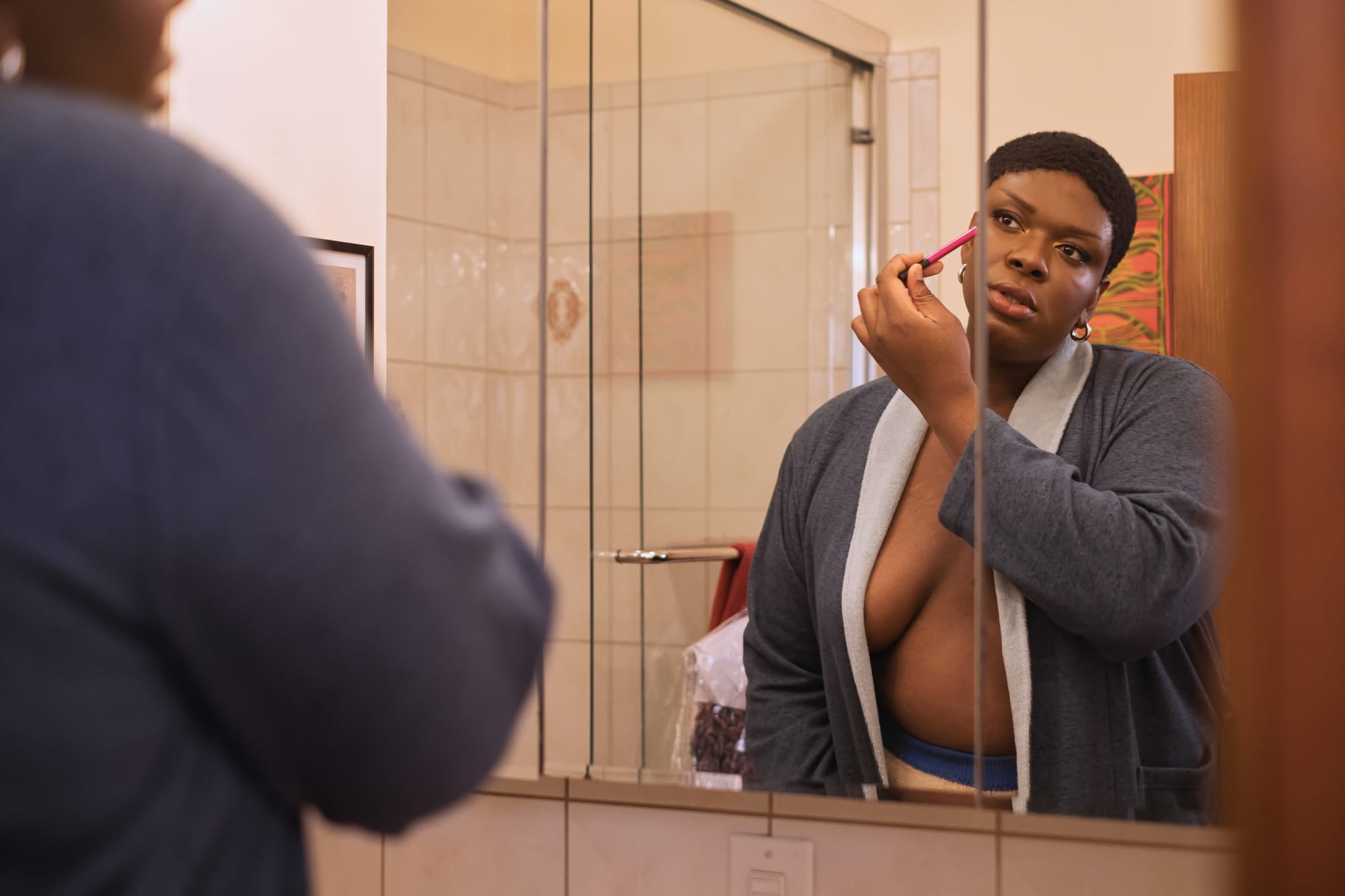 A Non Binary Trans Woman Applying Makeup In A Mirror